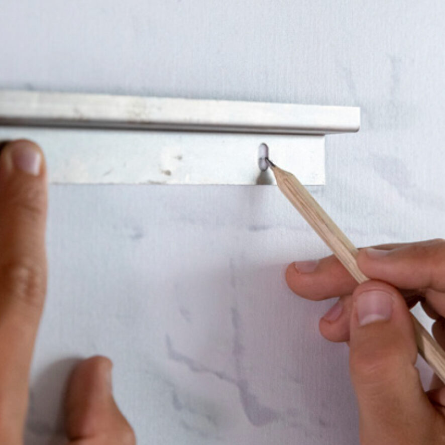Teken met een potlood de plek van de twee boorgaten in het Z-profiel op de muur.